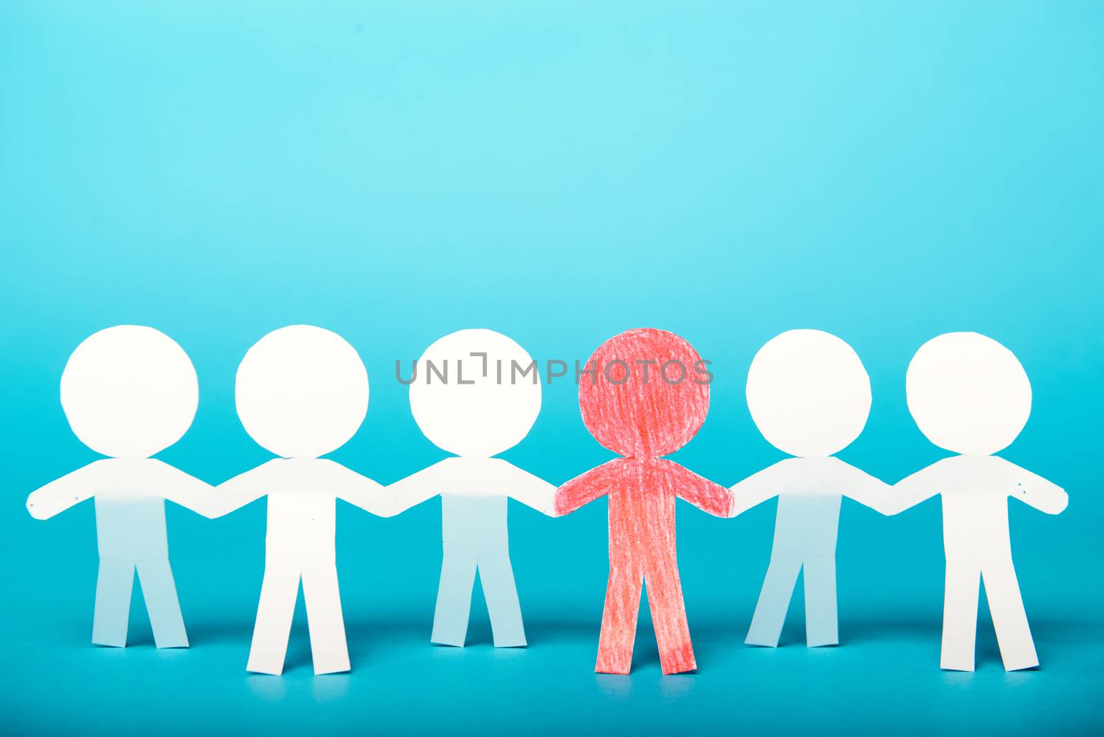 A group of red and white paper people holding hands indicating community support, partnership and togetherness.