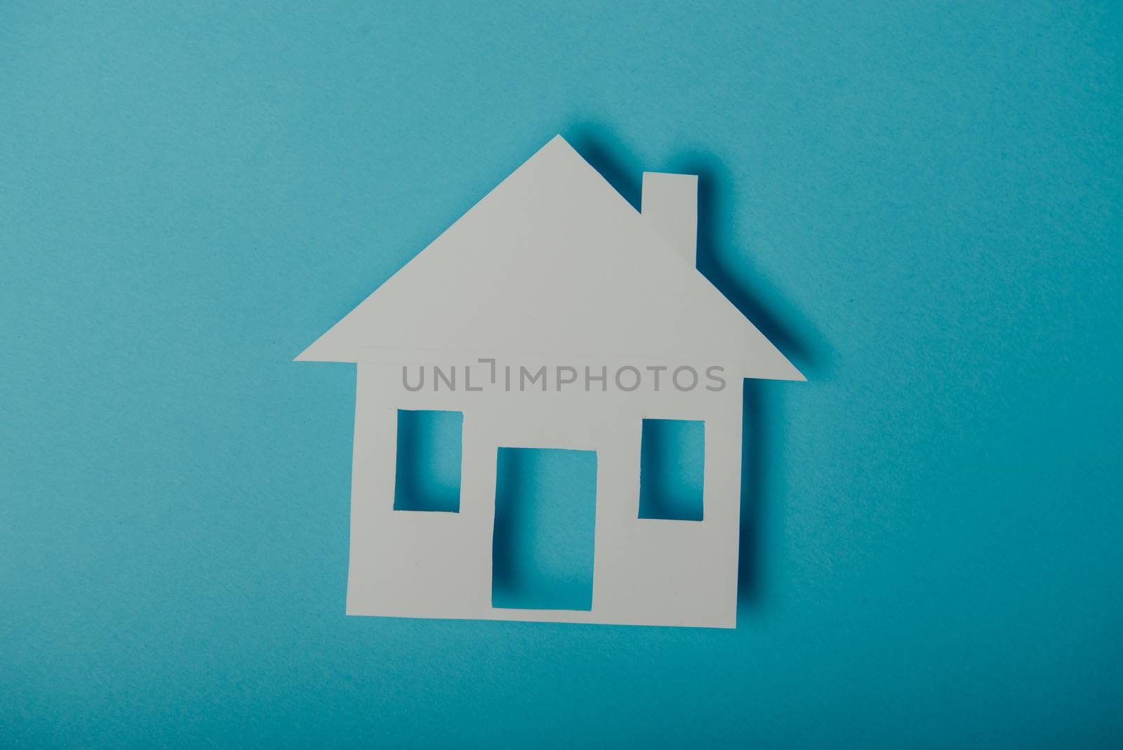 House shaped paper cutout on on blue background