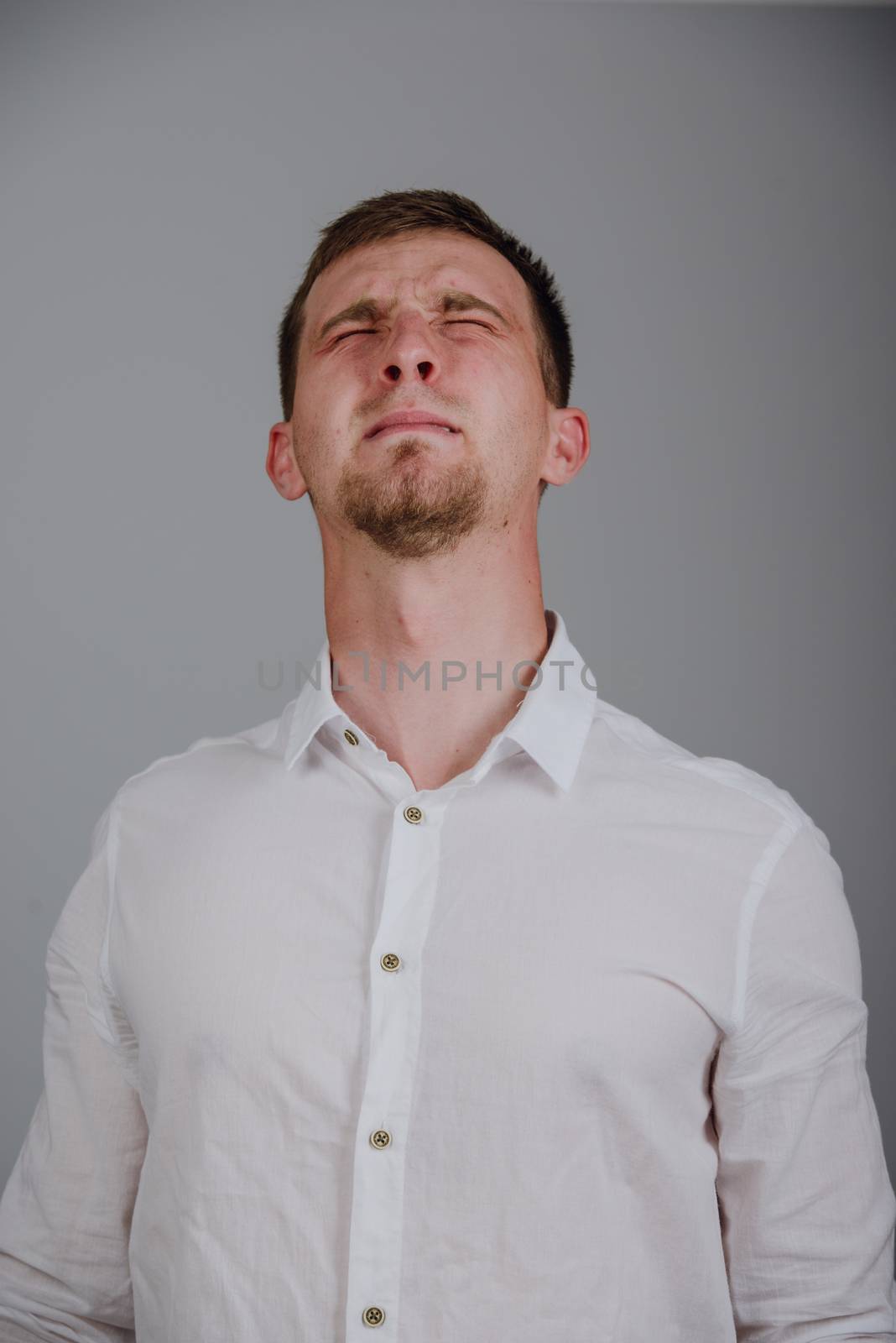 young man with a strong pain against gray background