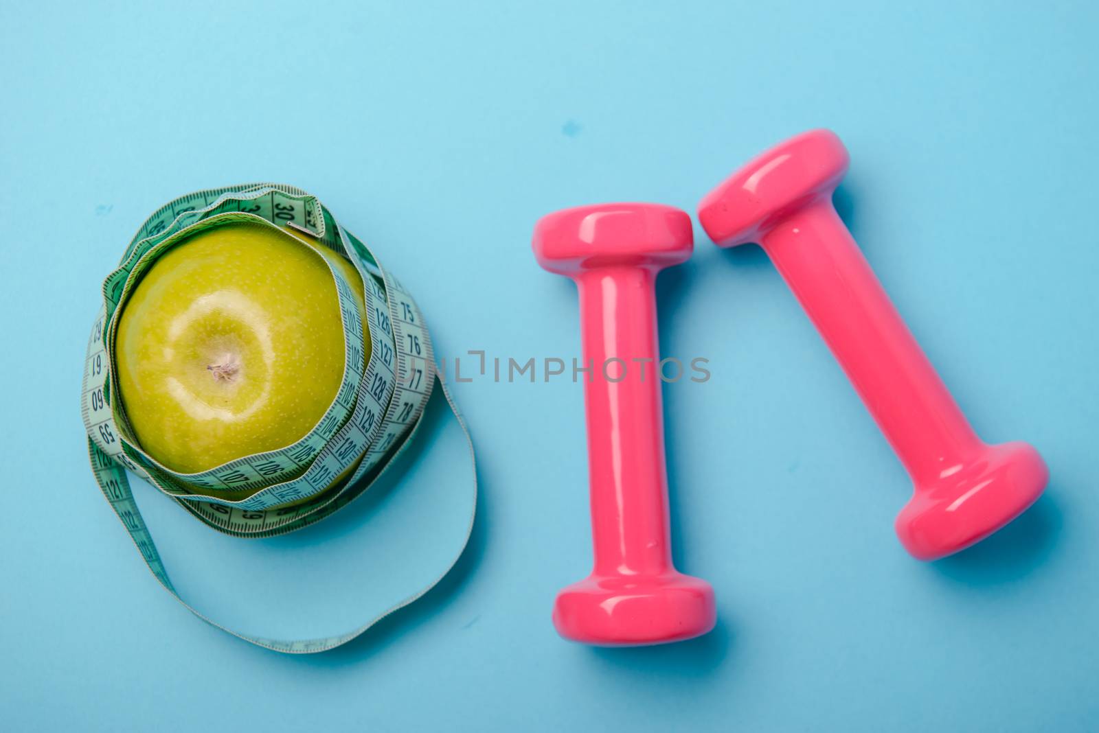 Pair of pink 1 kg dumbbells on blue background and water bottle