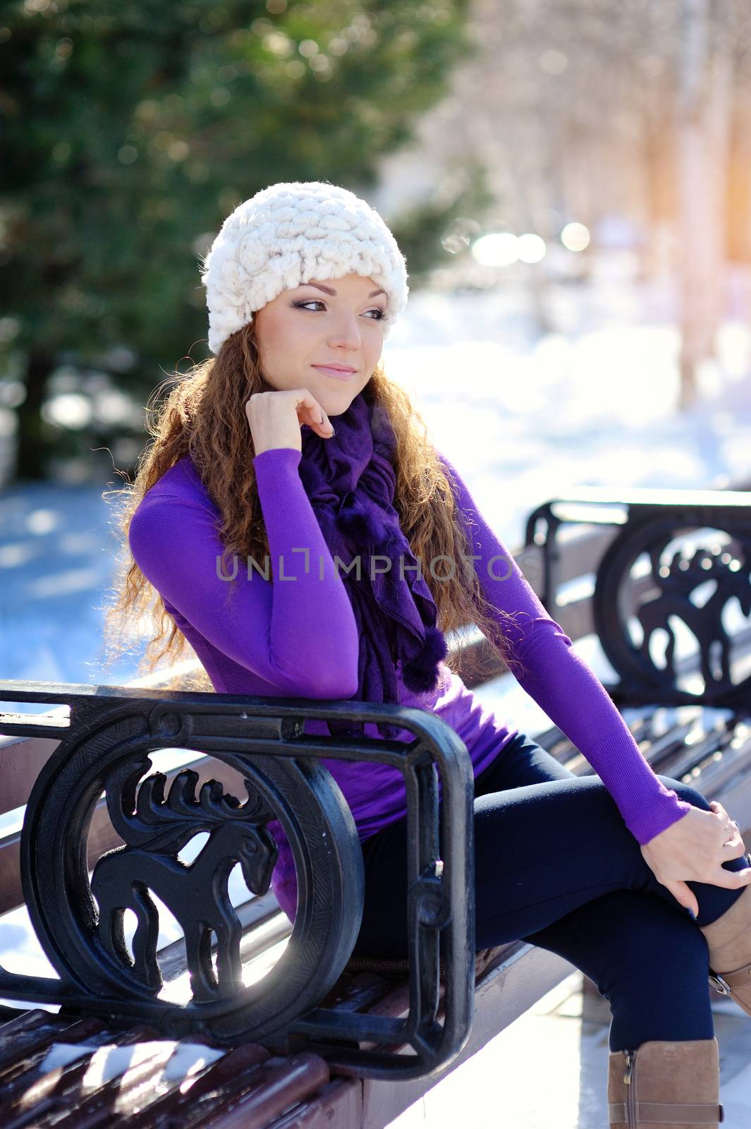 Beautiful girl sitting on a bench in winter