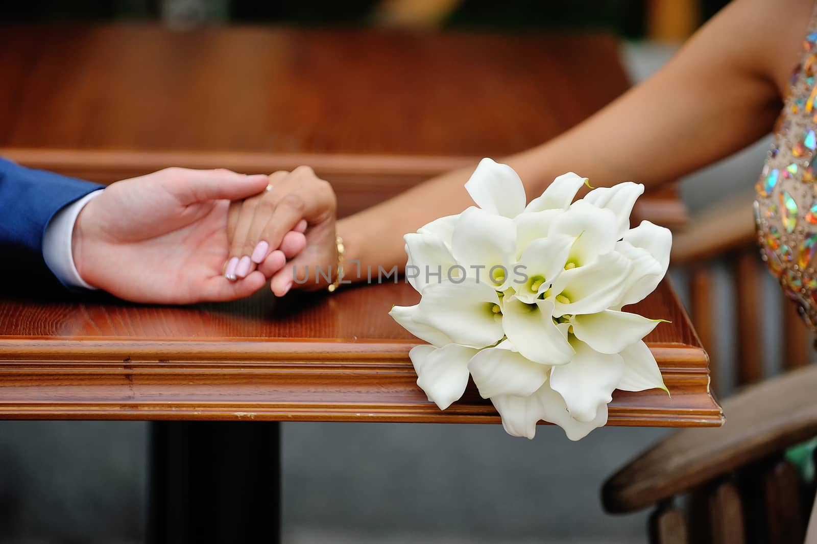 Wedding bouquet of calla lilies on a background of the bride and groom hands