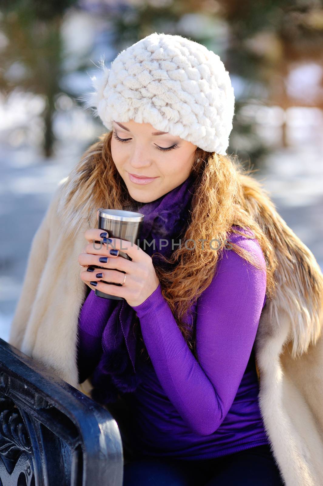 Beautiful girl drinking hot hour outdoors in the winter