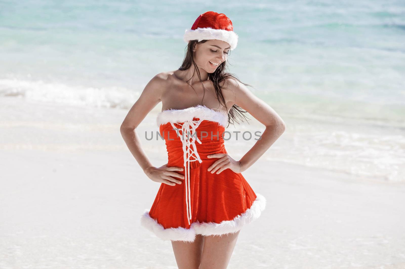 Beautiful woman in Mrs. Claus custume on tropical beach, Christmas vacations concept