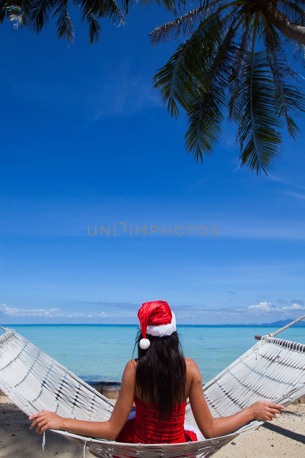 Woman in hammock on tropical beach celebrating Christmas