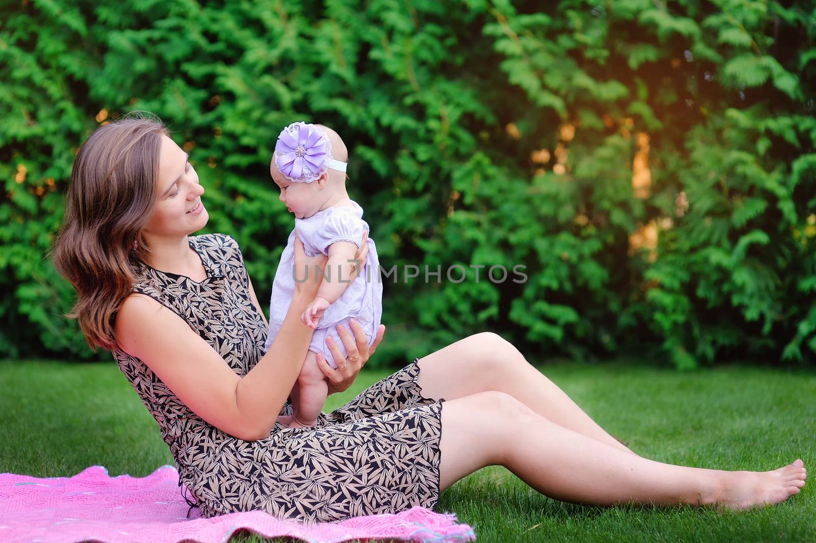 Mum holds on hands of a little daughter outdoors in park