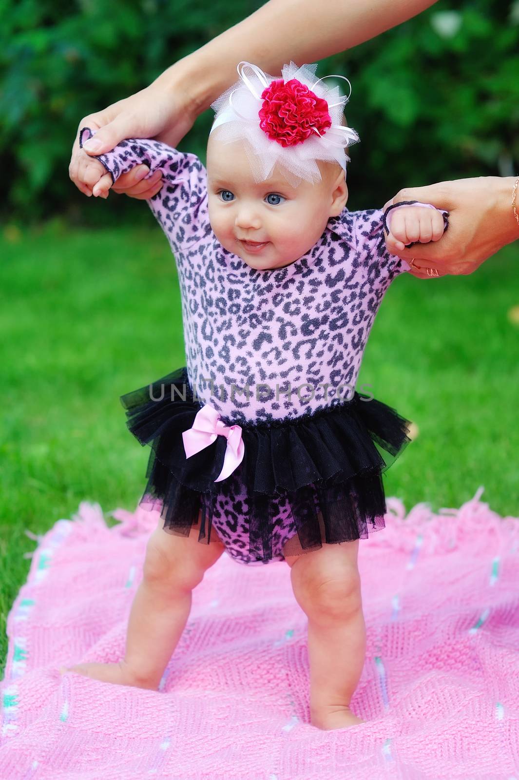 Beautiful brunette baby girl sitting in a field 