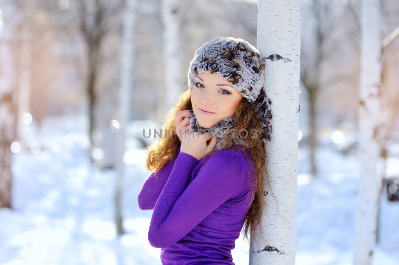 Outdoor winter portrait. Beautiful smiling girl posing in winter snowy forest 