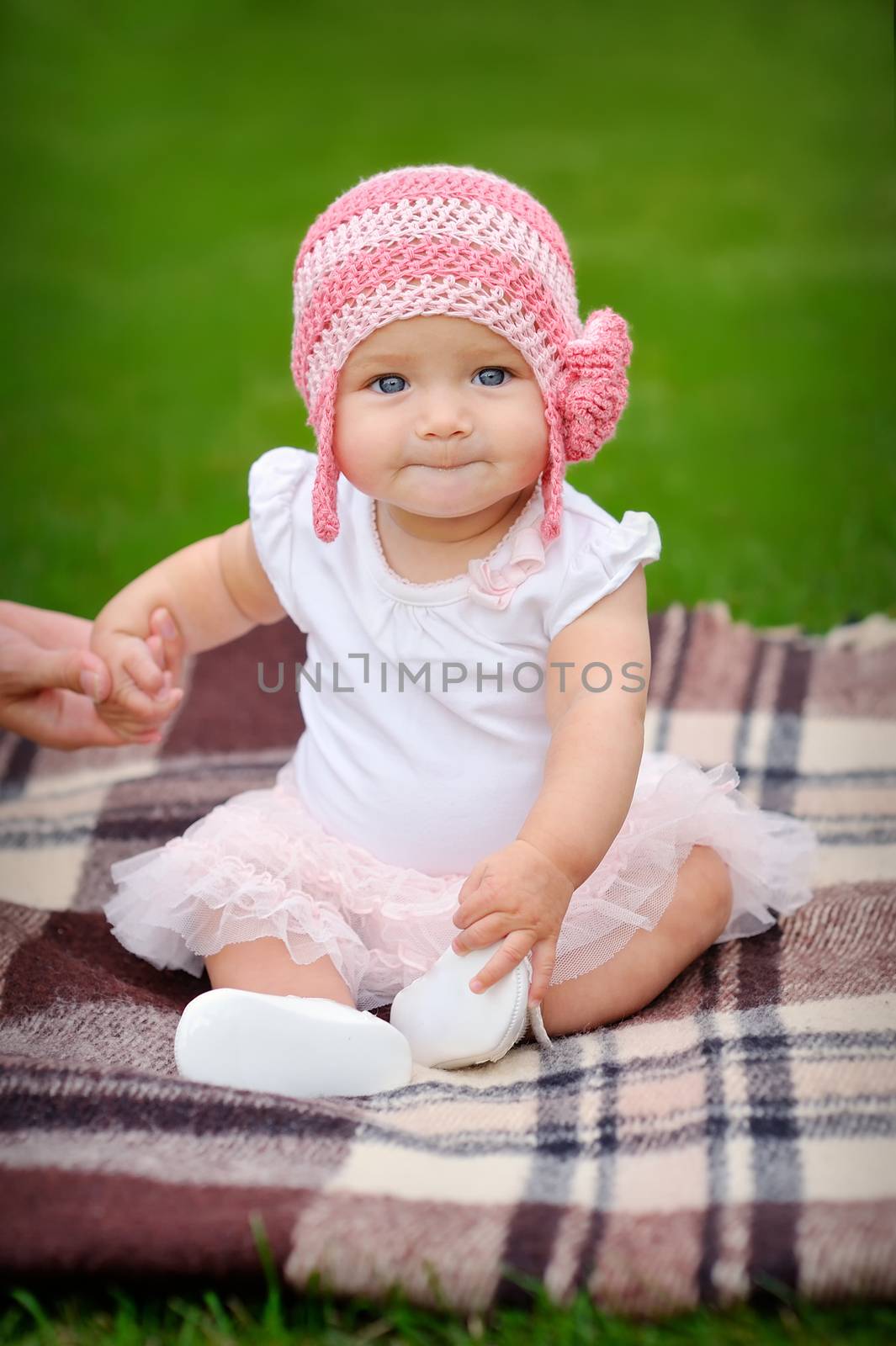 baby girl in the park in a pink knitted hat