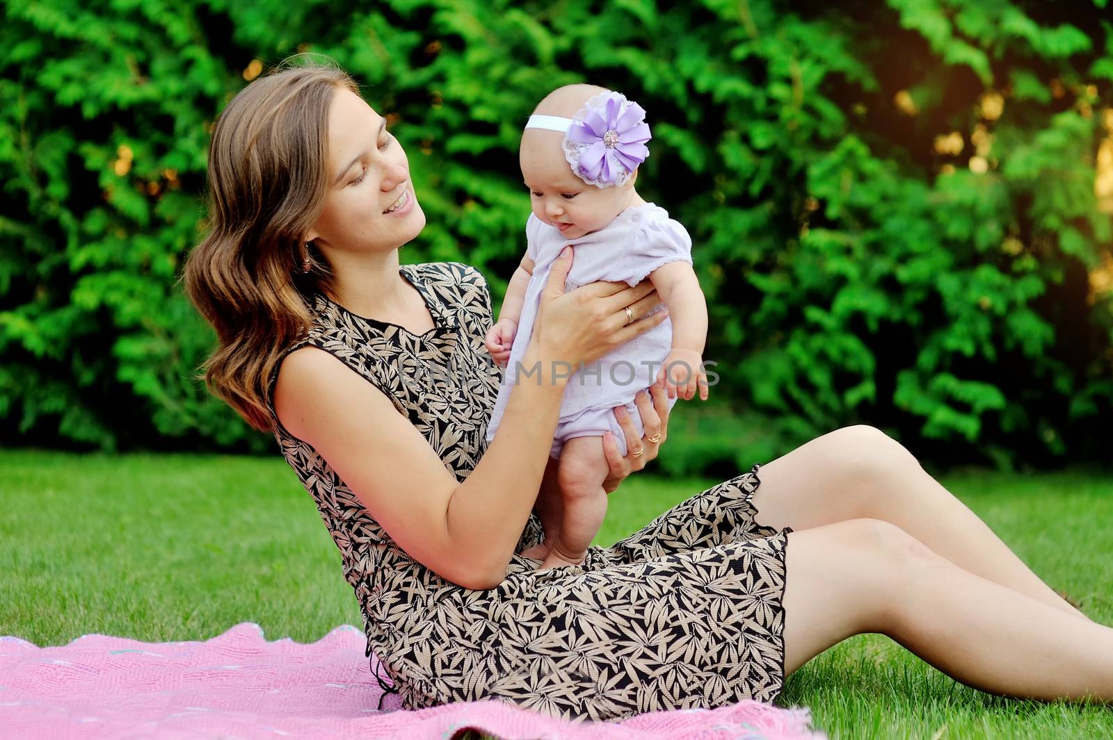 Beautiful Mother And Baby playing in a park. outdoors. Nature. Beauty Mum and her Child playing outdoors together. Outdoor Portrait of happy family. Joy. Mom and Baby 