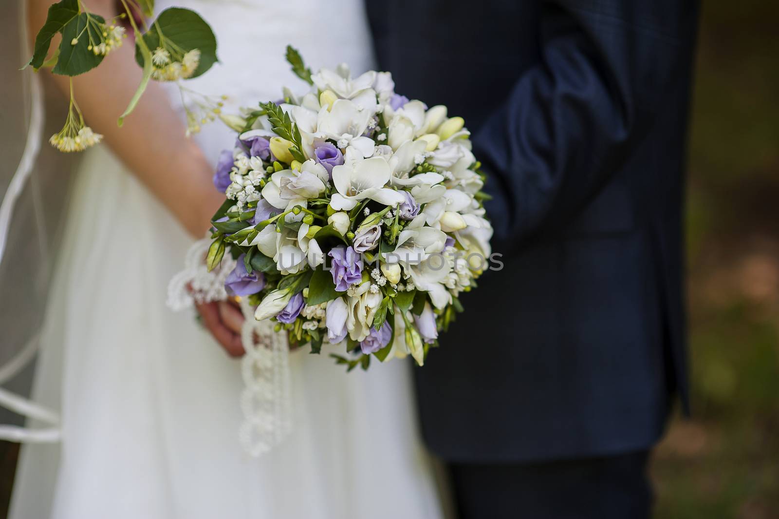 Wedding bouquet in hands of the bride and groom