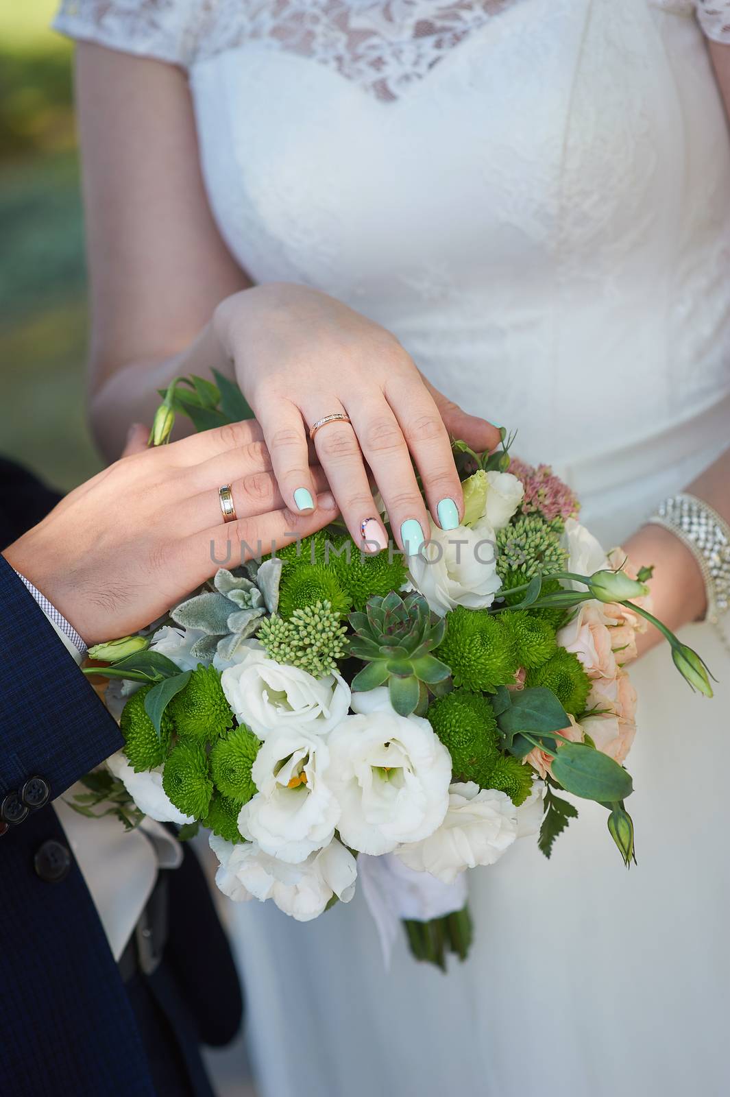 hands of the bride and groom with rings for wedding bouquet.