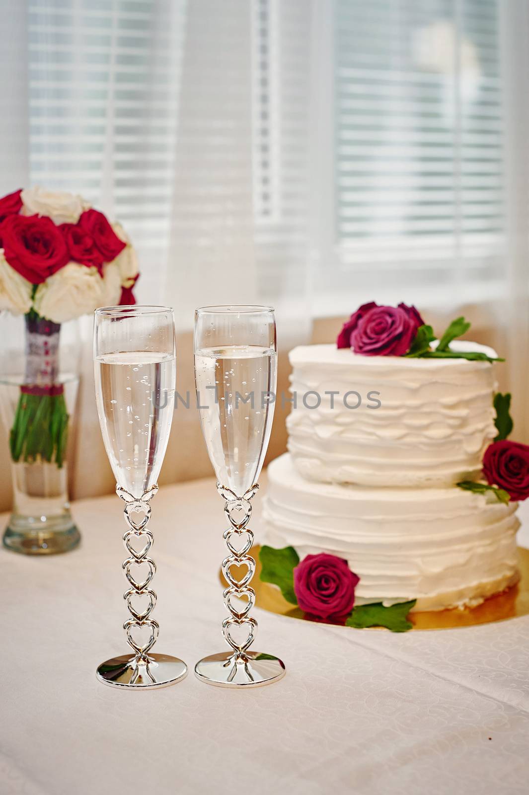 two glasses of champagne and wedding cake on the table.