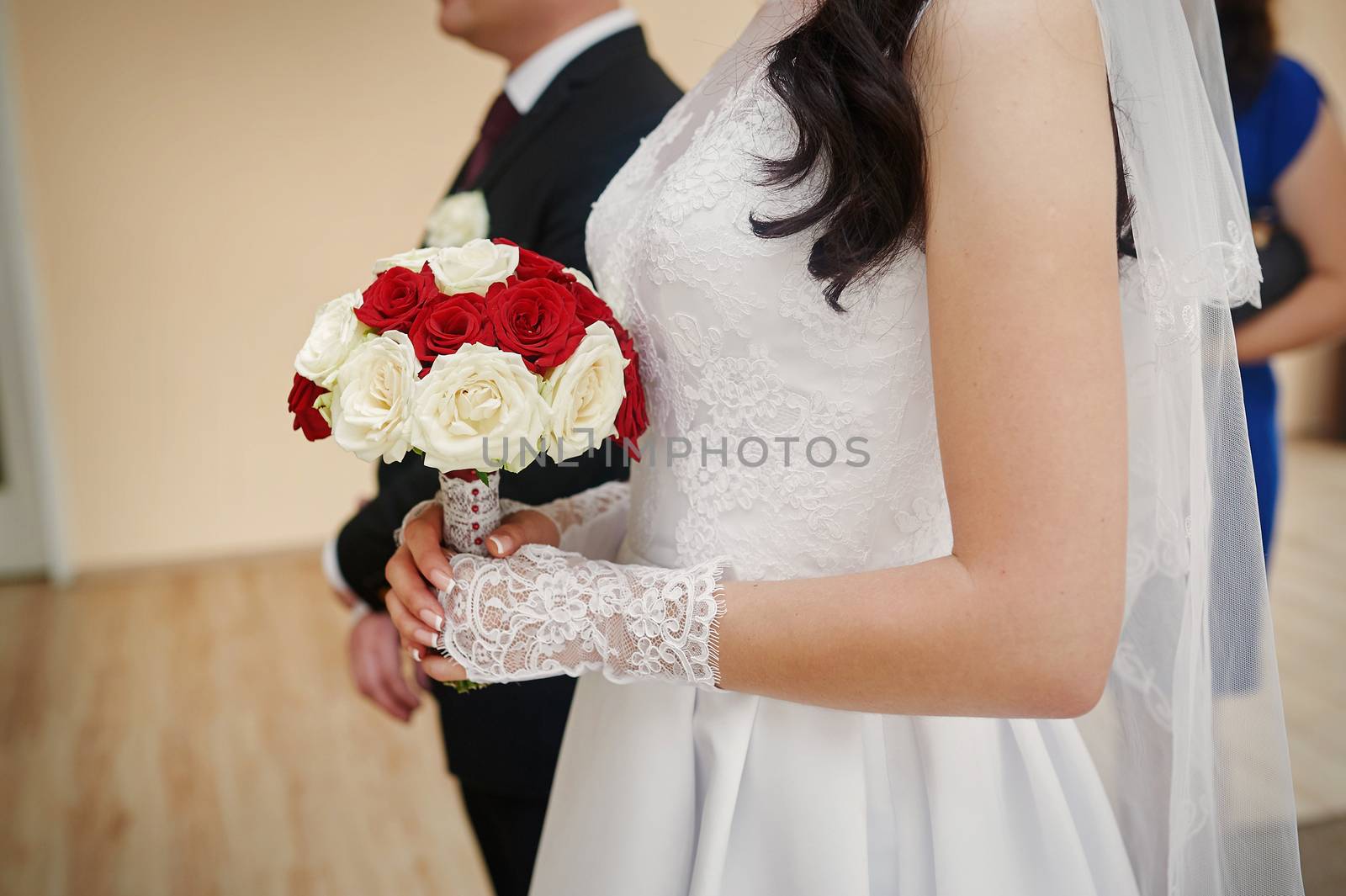 bride holding bouquet of white and red roses in a ceremony.