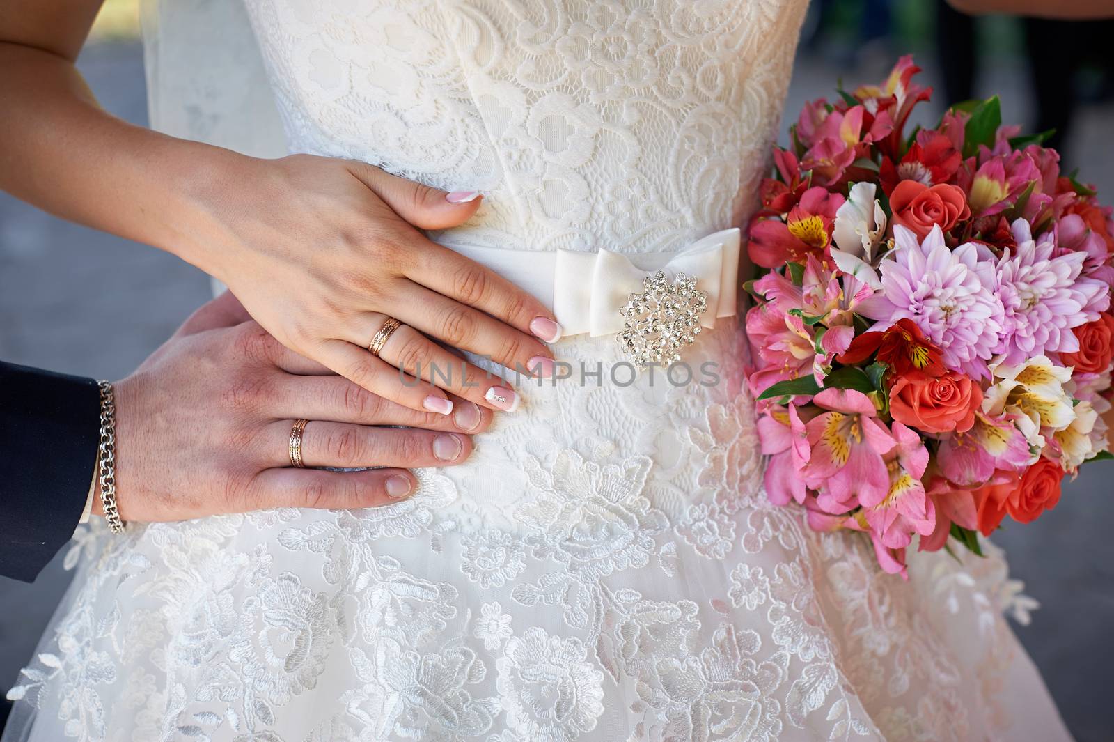 hands of the bride and groom with rings and wedding bouquet.
