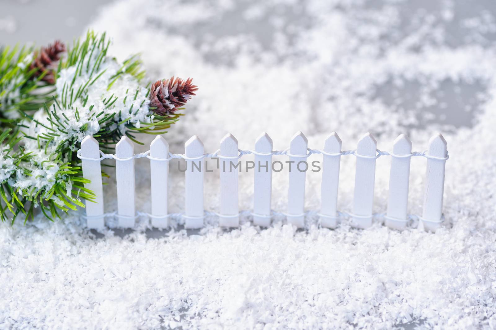 snow-covered spruce twigs and toy white fence. Christmas installation.