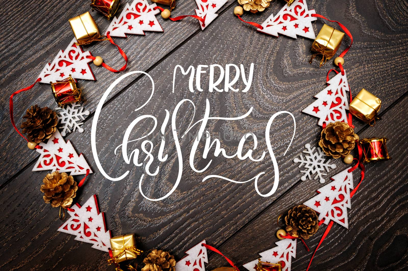 frame from toys fir trees on wooden background and text Merry Christmas. Calligraphy and lettering.