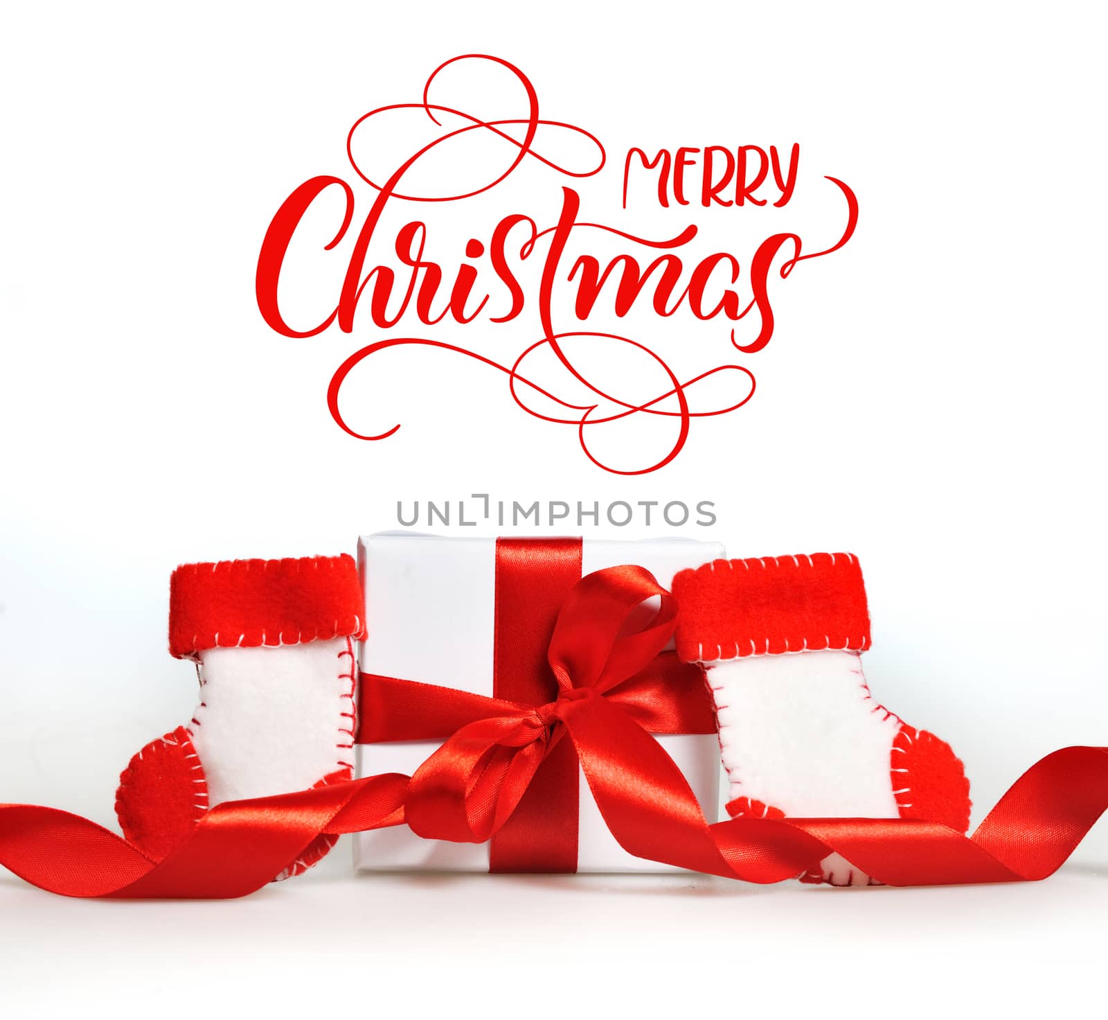 beautiful gift boxes with red ribbons and branch of tree and text Merry Christmas. Calligraphy lettering.