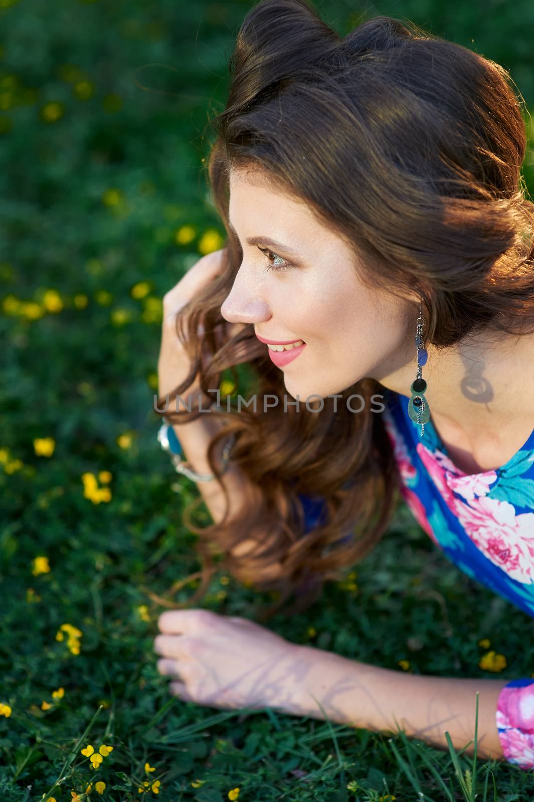 happy young woman lying on green grass by timonko