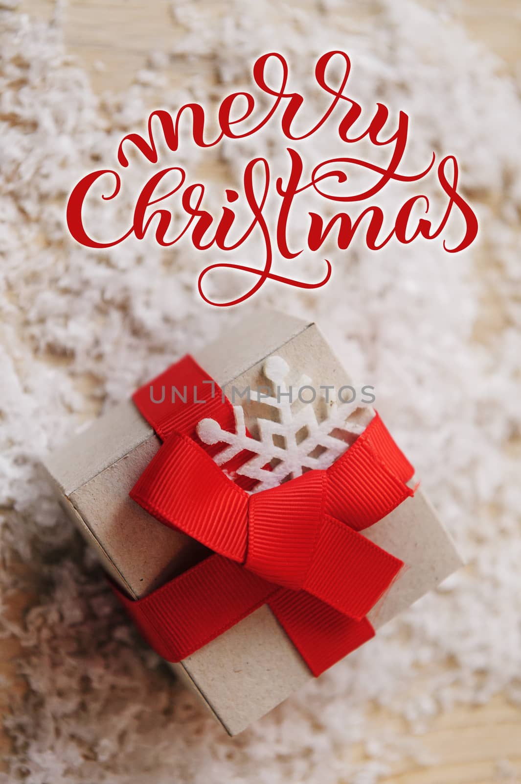 gift box of kraft paper with Red Ribbon and Merry Christmas text. Calligraphy lettering.