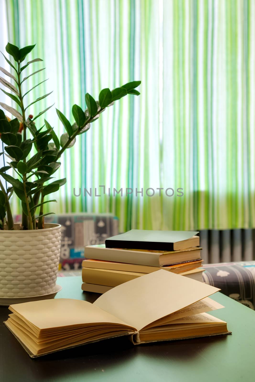 the open book and pile of books on a table in the room