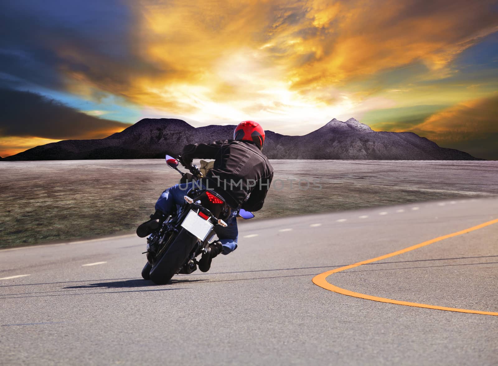 rear view of young man riding motorcycle in asphalt road curve w by khunaspix