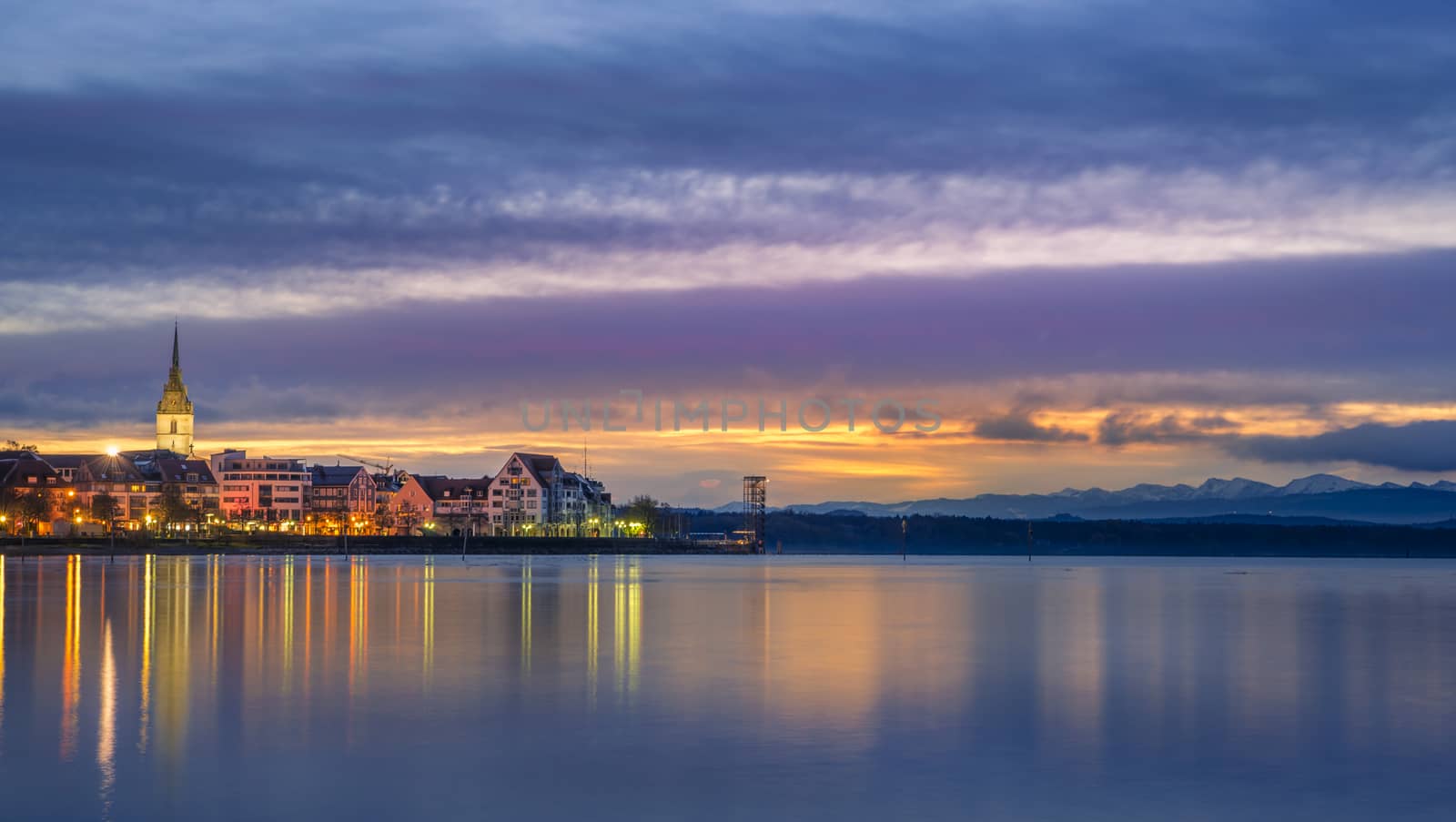 Multi-colored landscape with the Friedrichshafen town, Germany and the Bodensee lake at dawn.