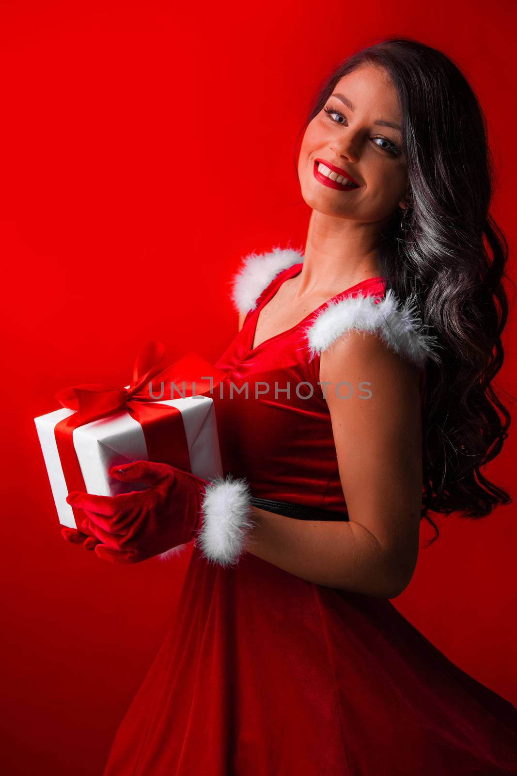 Beautiful woman in santa claus costume with christmas gift