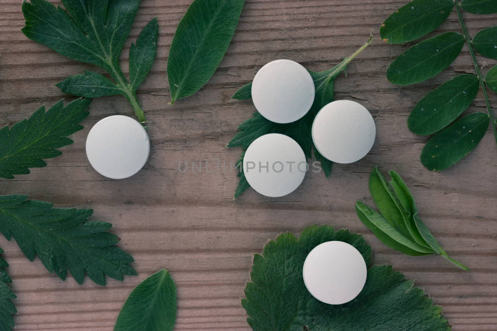 herbal medicine concept, pills and plants on wooden background