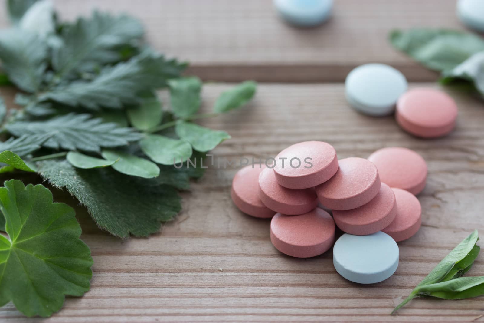 herbal medicine concept, pills and plants on wooden background