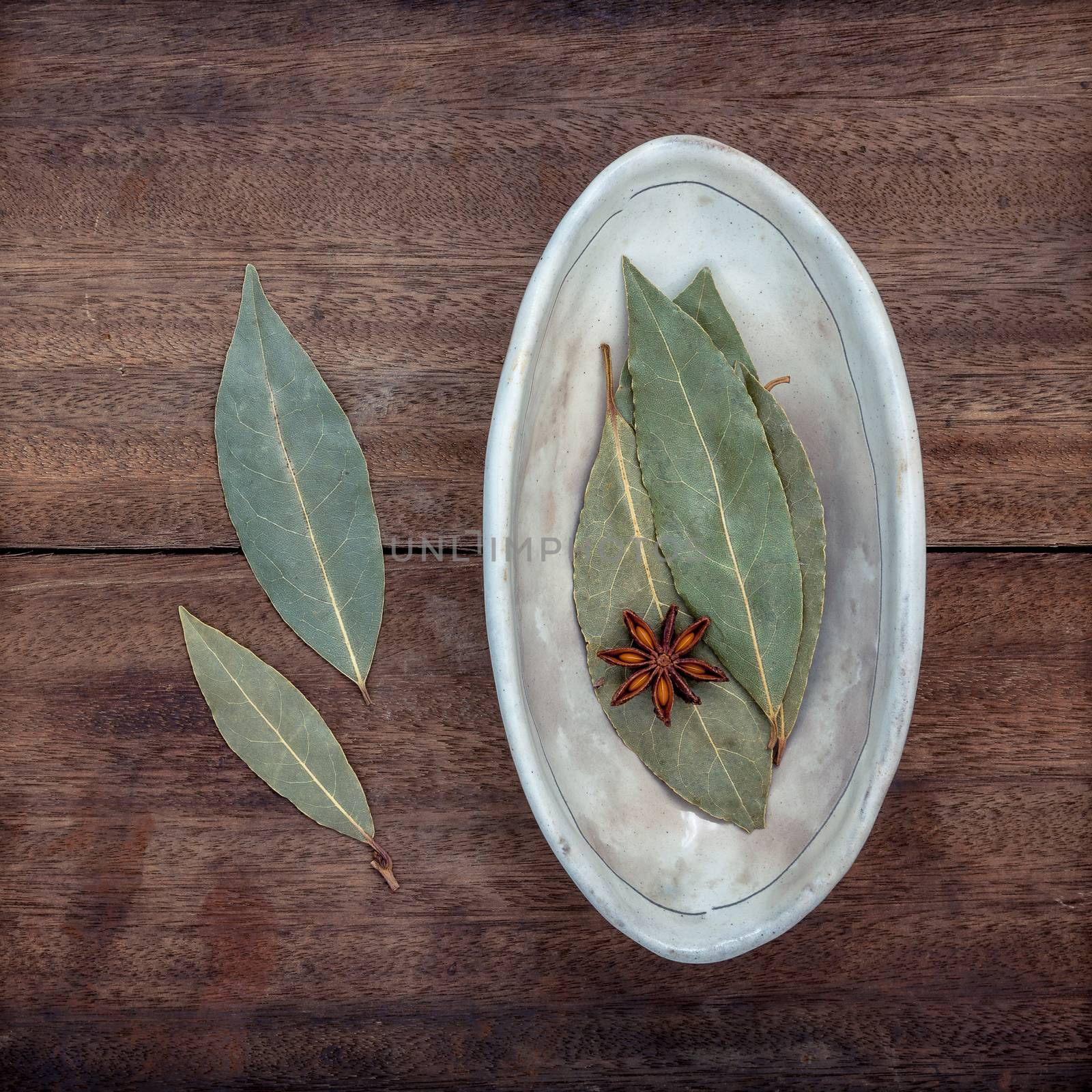 The Bowl of dried bay leaves on old wooden background.