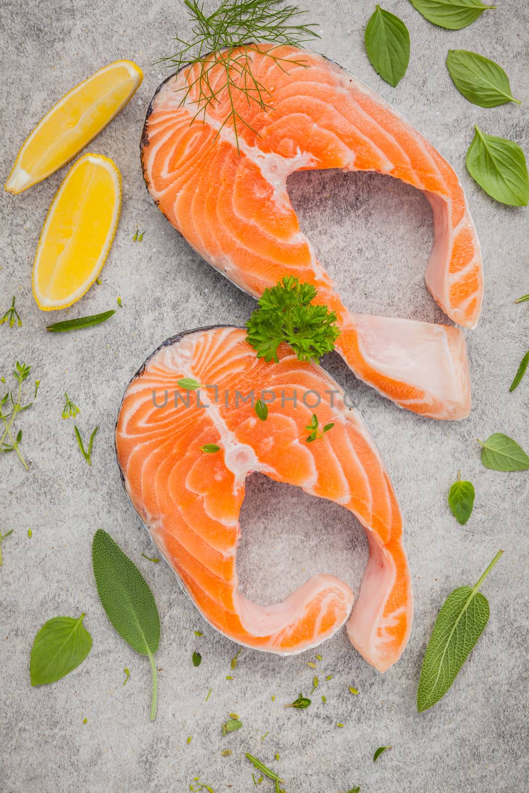 Fresh salmon fillet slice on dark stone background with herbs fennel ,sage ,rosemary thyme,parsley and lemon propose  for cooking . Healthy food concept.