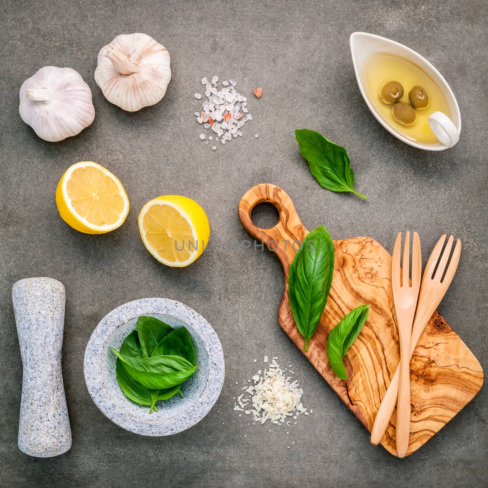 The ingredients for homemade pesto sauce : basil, parmesan cheese ,garlic, olive oil , lemon and himalayan salt over dark concrete background.