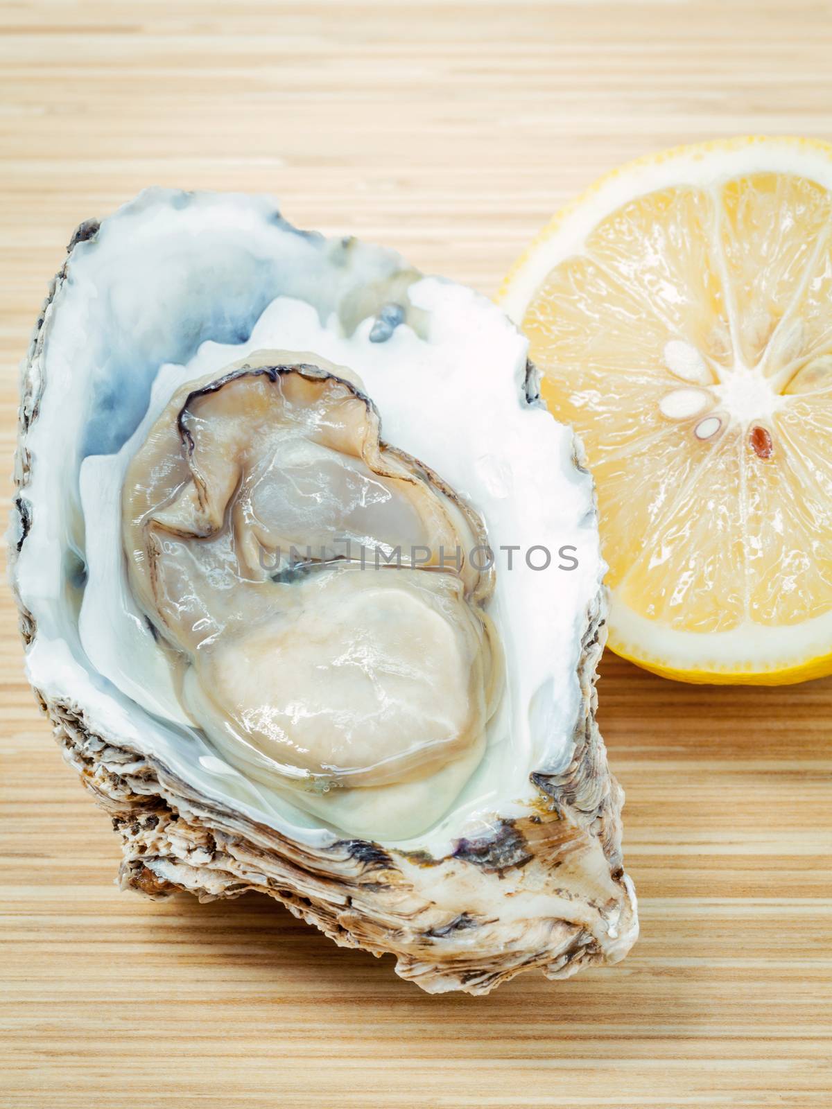 Fresh Oysters with lemon on  wooden background. Opened Oysters with selective focus on wooden texture .