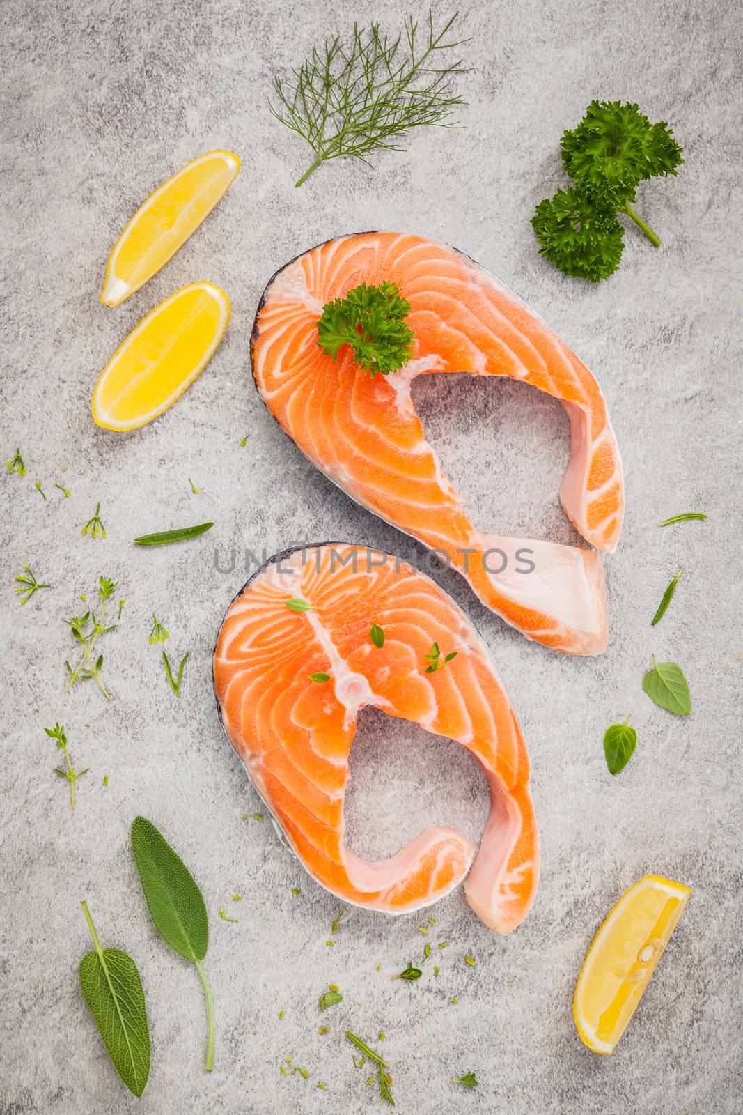 Fresh salmon fillet slice on dark stone background with herbs fennel ,sage ,rosemary thyme,parsley and lemon propose  for cooking . Healthy food concept.