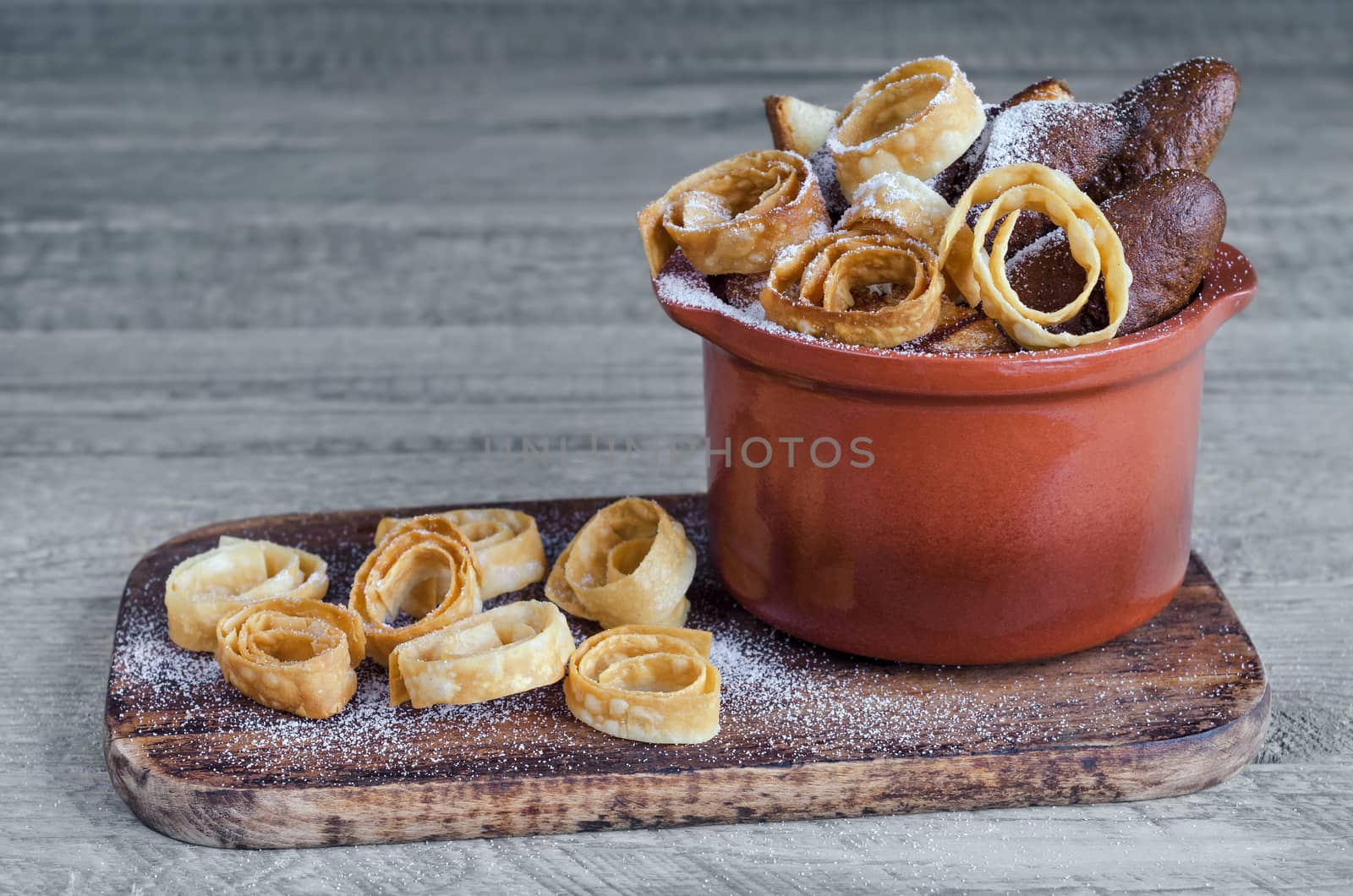 Cookies, dusted with powdered sugar. On the Board and in the ceramic pot. Grey wooden background.