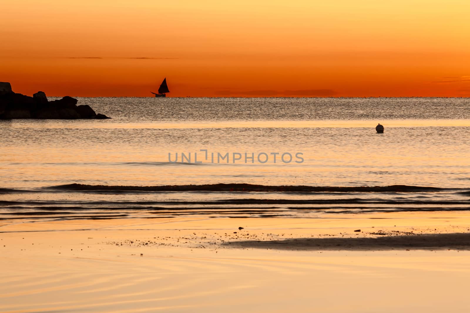 Scenic view of beautiful sunrise on the sea with a sailing boat on the horizon