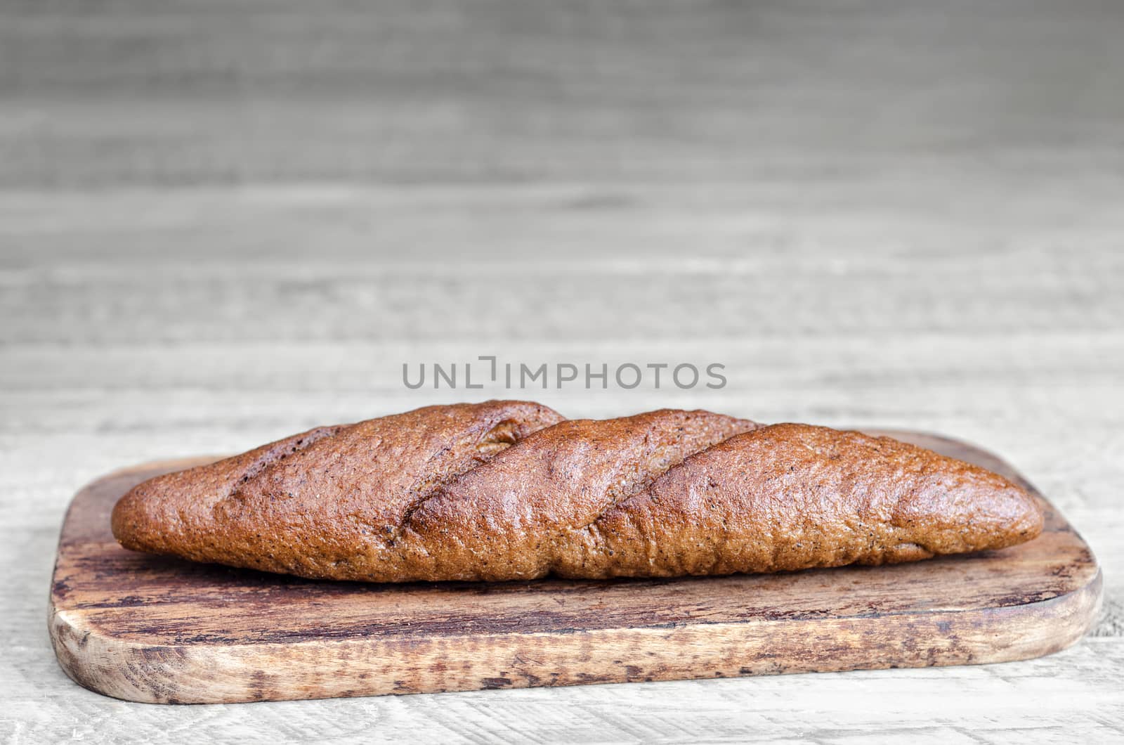 Black bread on the cutting Board, and a gray wooden background