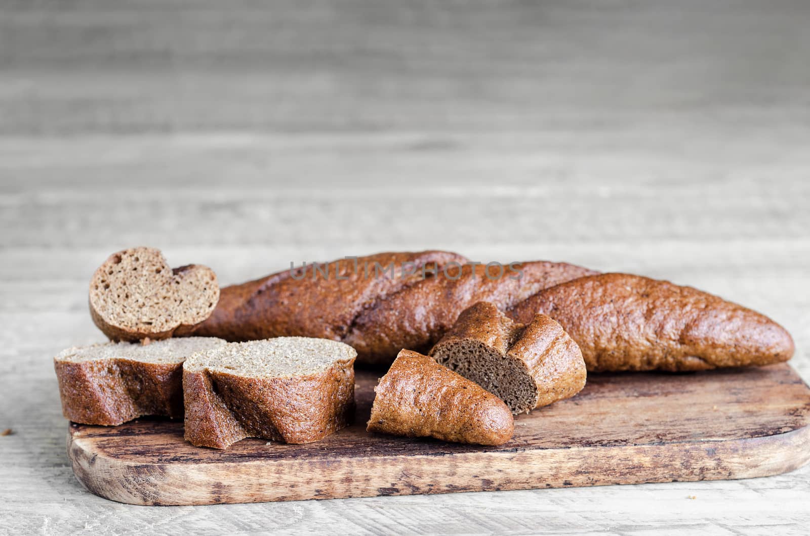Whole and sliced bread on a cutting Board, and a grey wooden background