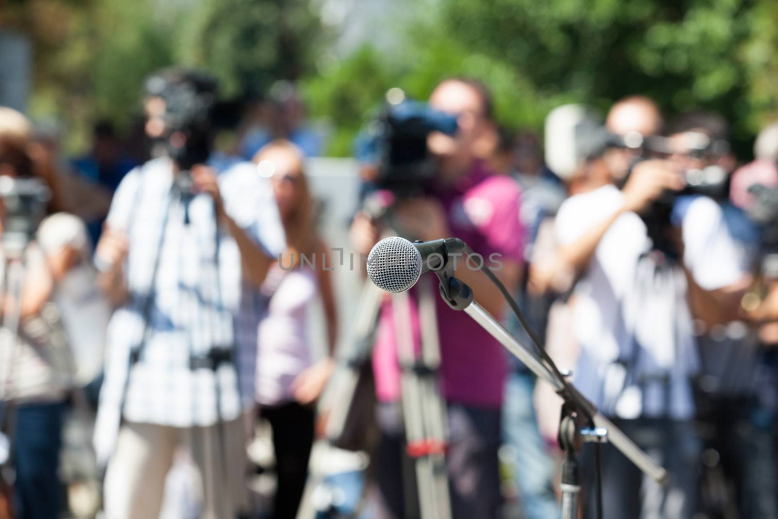 Microphone in focus against blurred camera operators and reporters