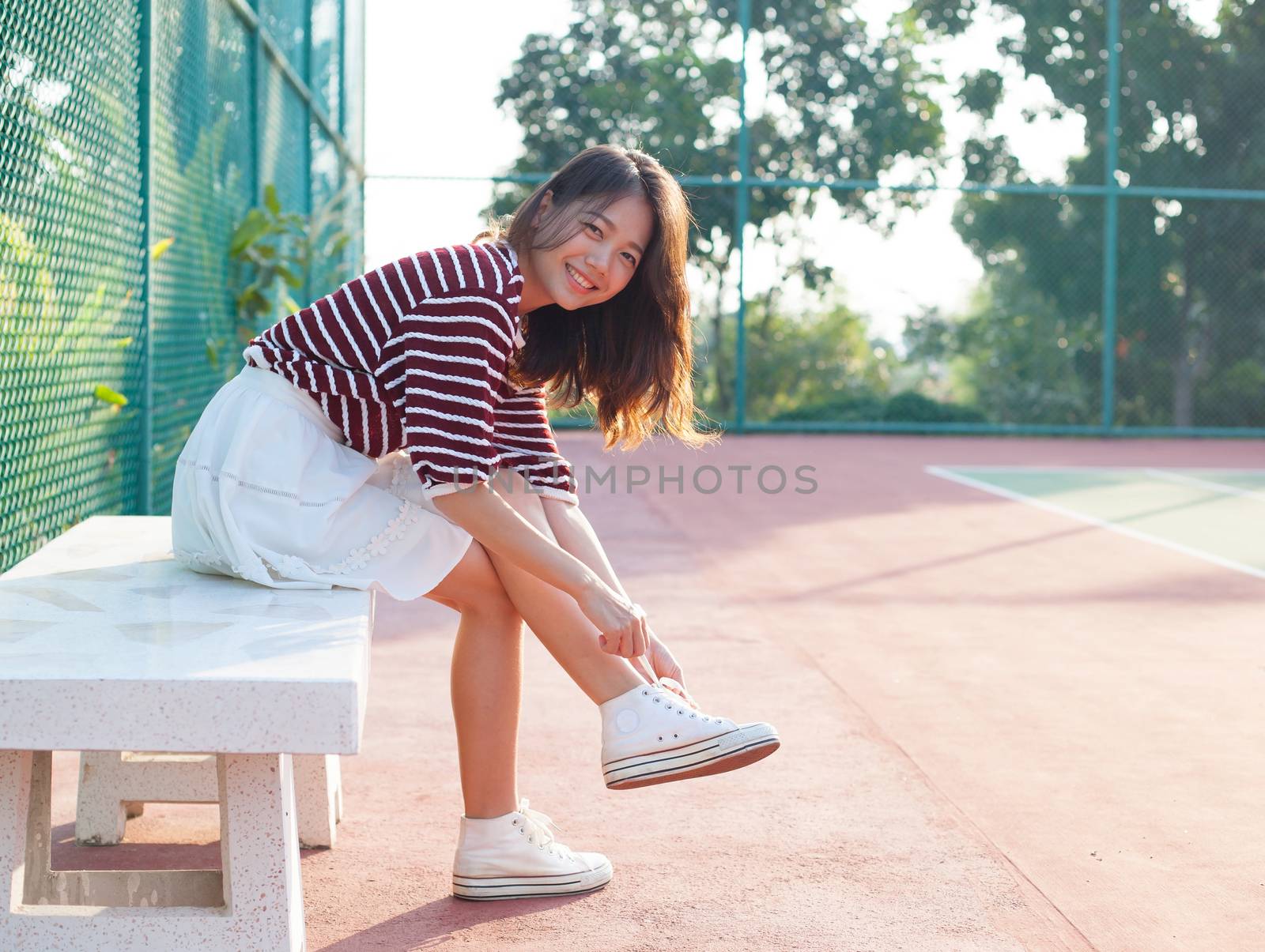portrait of beautiful sport girl sitting in tennis courts  looking to camera with smiling face use for people and healthy lifestyle activities
