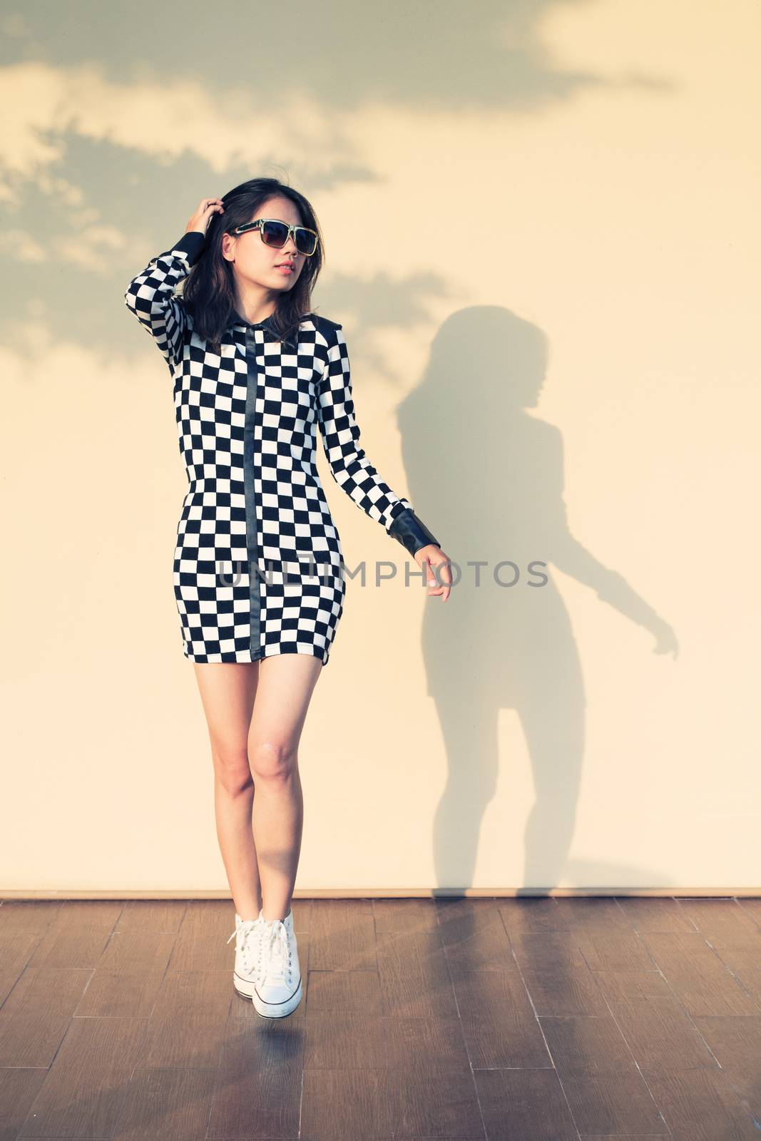 young and beautiful hipster woman against light and shadow on warm yellow wall