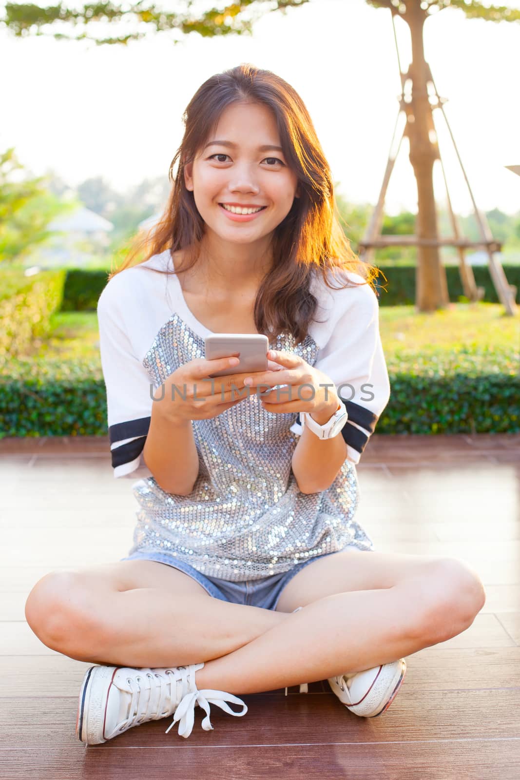 young teen woman and smartphone in hand smiling with happy emoti by khunaspix