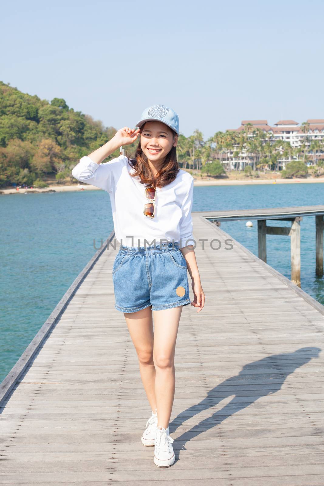 young beautiful woman standing on wood pier with blue sea water behind use for people relaxing on vacation place