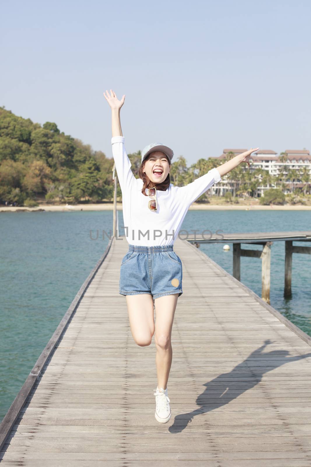 portrait of young beautiful woman jumping with happy emotion on wood piers at sea side use for people activities in holiday vacation