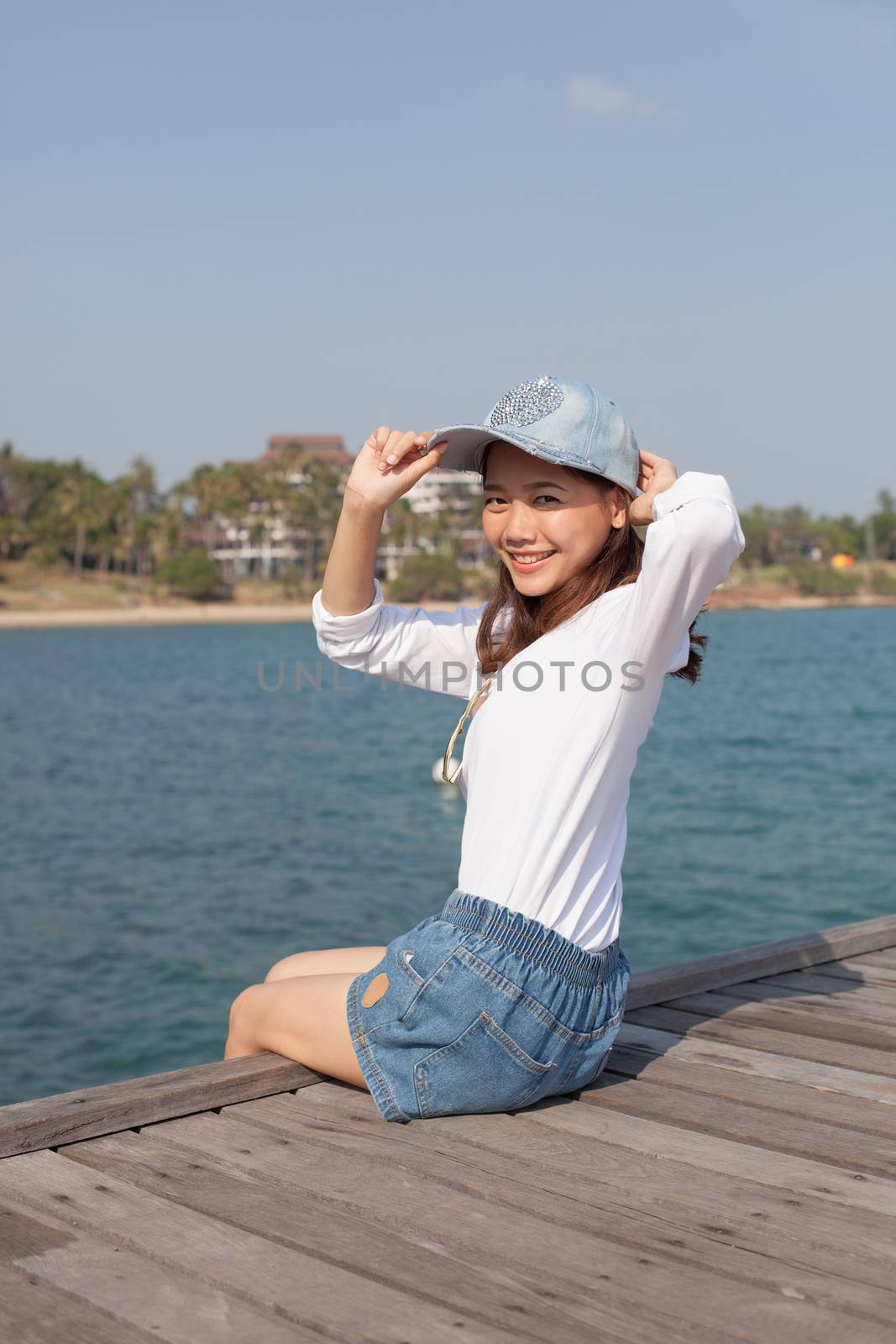 portrait of beautiful woman happy face sitting on wood port sea side use for people activities holiday ,vacation on beach