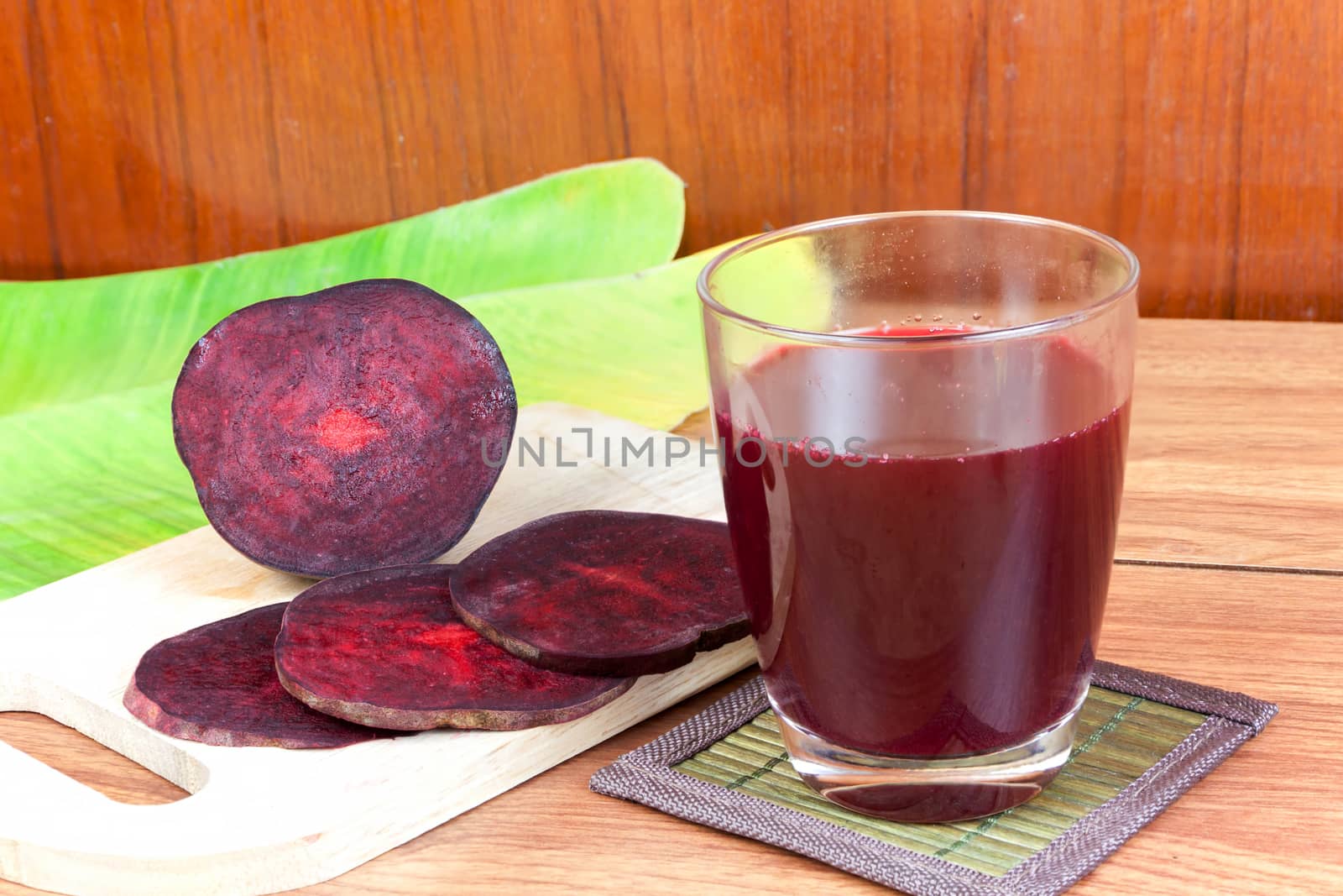 Fresh slices red beetroot and beetroot fruit juice in glass a wood background