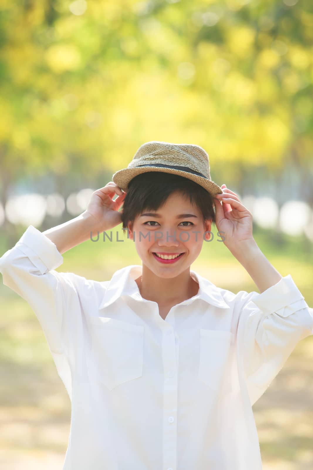 portrait of young beautiful asian woman wearing fashion straw hat with happiness smiling face in blooming yellow flowers park use for people relax activities summer holiday