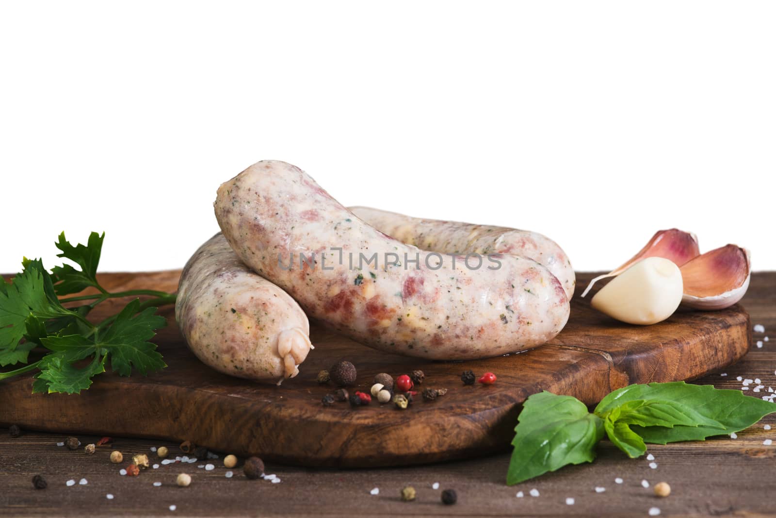 Raw sausages with garlic and parsley on the cutting board, isolated