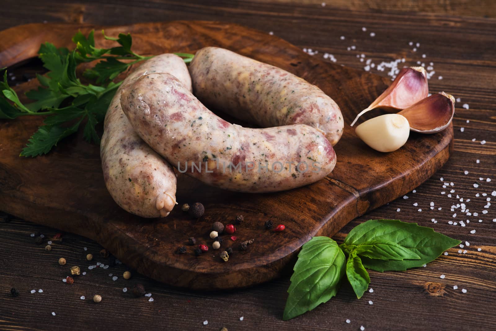 Raw sausages with garlic and parsley on the cutting board